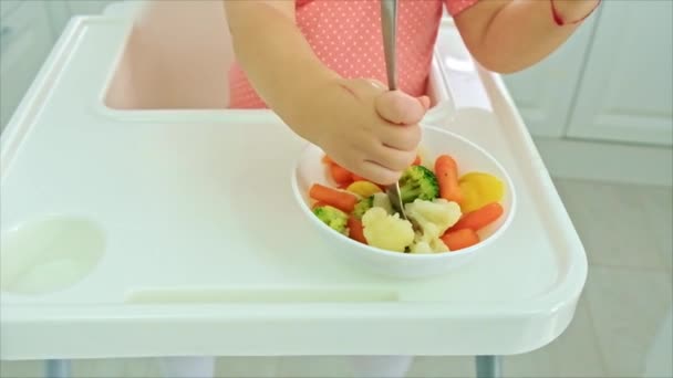 Le bébé mange des légumes sur une chaise. Concentration sélective. — Video