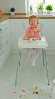 Bebek sandalyede sebze yiyor. Seçici odak.