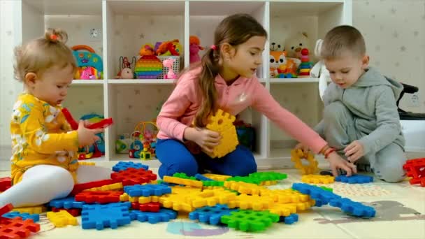Kinder spielen zusammen, während ein Bauunternehmer ein Haus baut. Selektiver Fokus. — Stockvideo