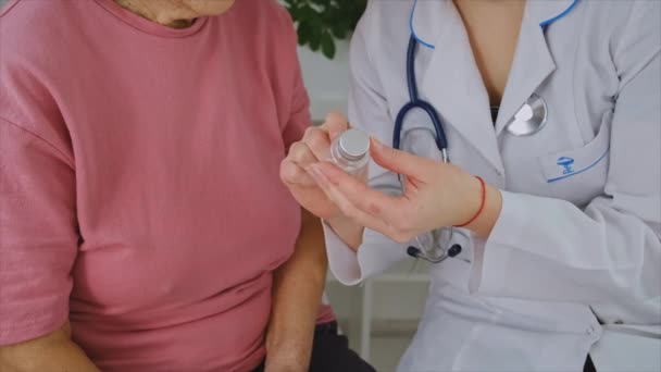 医者は老婦人に薬を飲ませる。選択的焦点. — ストック動画