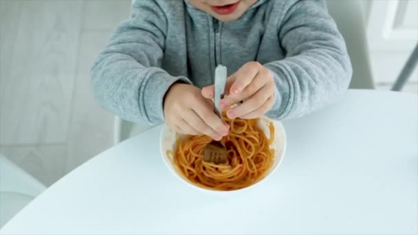 Il bambino mangia gli spaghetti in cucina. Focus selettivo. — Video Stock