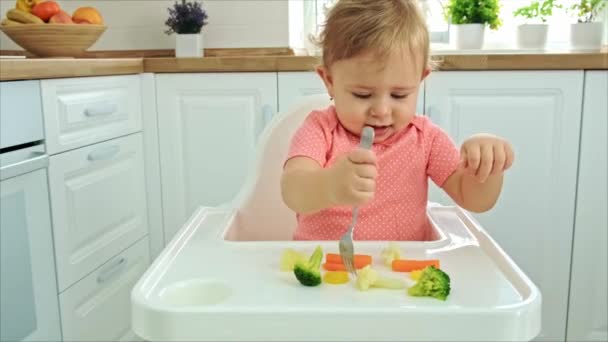 Baby eet groenten op een stoel. Selectieve focus. — Stockvideo