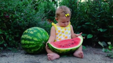 Küçük kız yazın karpuz yer. Seçici odak.
