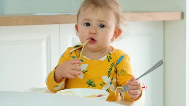 A criança come espaguete na cozinha. Foco seletivo. — Vídeo de Stock