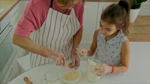Grandmother and child cook dough together. Selective focus. — Stock Video