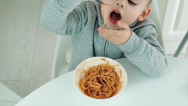 A criança come espaguete na cozinha. Foco seletivo. — Vídeo de Stock