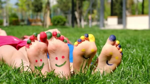 풀밭에 앉아 있는 아이의 다리는 미소를 짓습니다. 선택적 초점. — 비디오