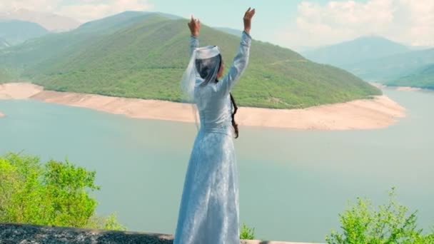 Een meisje in een Georgische nationale witte jurk danst. Selectieve focus. — Stockvideo