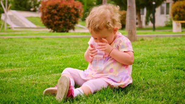 L'enfant boit de l'eau dans un verre. Concentration sélective. — Video