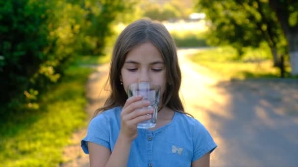 Das Kind trinkt Wasser aus einem Glas. Selektiver Fokus. Kind.