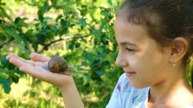 Çocuk doğayı inceliyor. Salyangoza bakıyor. Seçici odaklanma. Çocuk.