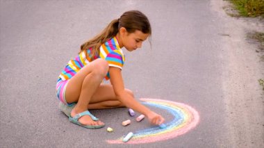 The child draws with chalk on the pavement. Selective focus. Kid.