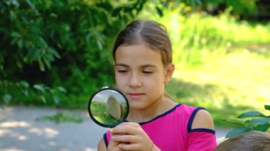 Child look at a snail with a magnifying glass, selective focus. Kid.