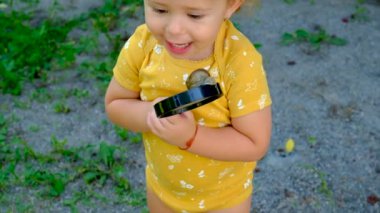Child look at a snail with a magnifying glass, selective focus. Kid.
