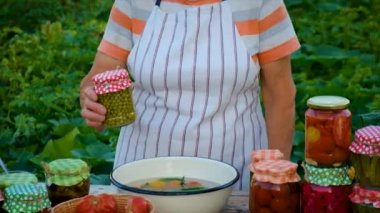 Senior woman makes preservation of vegetables. Selective focus. People.