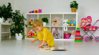 The child is looking at a book in the room. Selective focus. Kid.