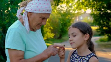 Grandmother and child are studying the snail in the park. Selective focus. Nature.
