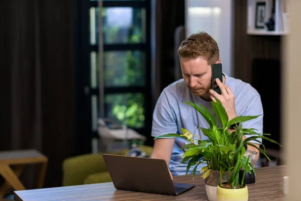 Portrét Ležérní Zamyšlený Muž Pomocí Chytrého Telefonu Při Pohledu Notebook — Stock fotografie