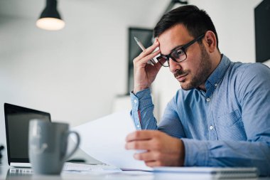 Stresli ve endişeli bir iş adamı portresi. Aşırı çalışan iş adamı görünümlü evraklar modern parlak ofiste baskı altında ve sıkı teslim tarihi altında çalışıyor.