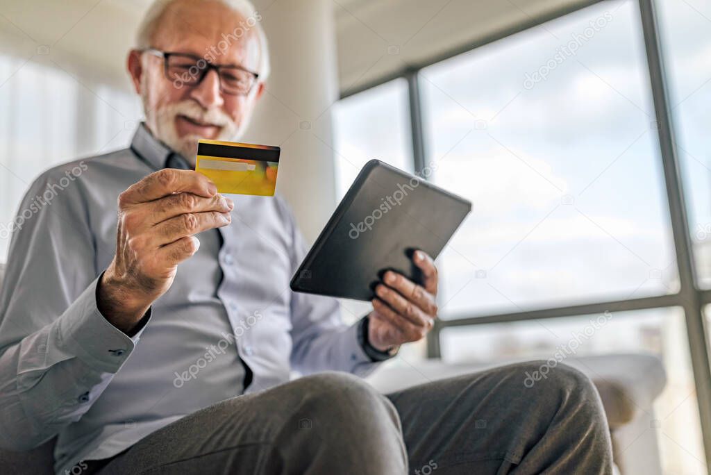 Blured portrait of elderly cheerful and happy male buying and paying online, transferring funds and money to family members.