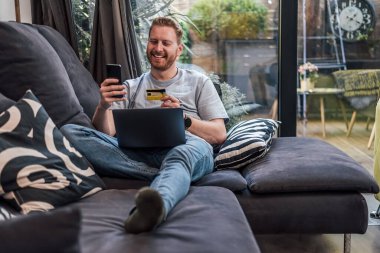 Sakallı yetişkin adam, yeni kartıyla kendi fotoğrafını çekiyor..