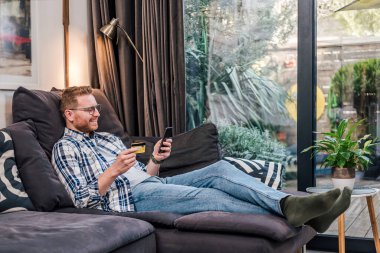 Sevimli yetişkin bir adam, bir online mağazada satış yapıyor, kredi kartını kullanıyor..