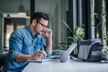Yoğun iş haftasını ofiste düzenleyen konsantre yetişkin bir adam..