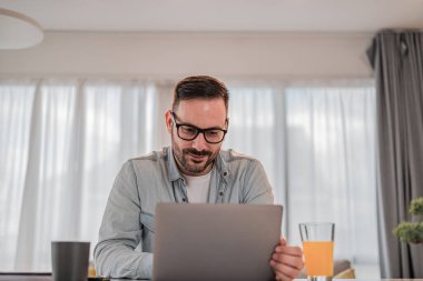 Yakışıklı yetişkin bir adam, gözlüklü, yeni laptopunu kullanıyor,.