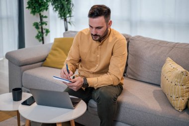 Sakin yetişkin bir adam, notlarını bilgisayarındaki notlarla karşılaştırıyor..