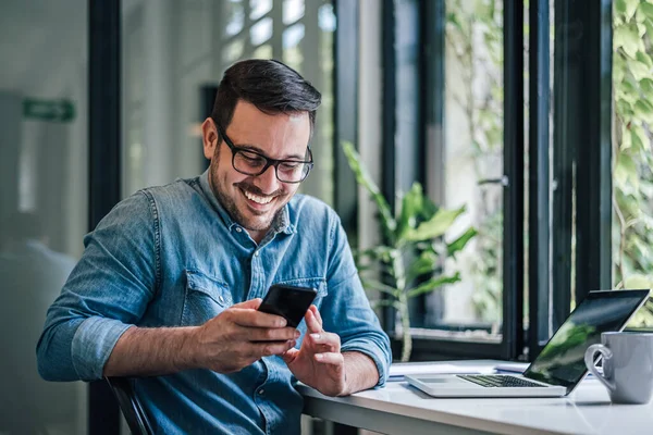 Ofiste çalışırken cep telefonunda gülümseyen profesyonel mesajlar.