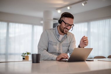 Telecommuting customer service Cheerful young adult businessman entrepreneur freelancer making online video call. Portrait of man working from home office providing call support call center operator.