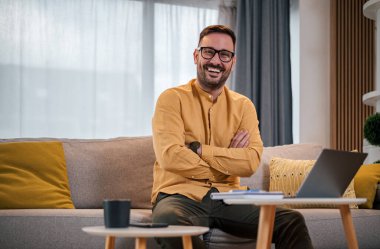 Genç yetişkin bir adamın portresi gülümseyen mutlu yakışıklı başarılı iş adamı iş adamı ofis bilgisayarından kameraya bakarak çalışan serbest girişimci