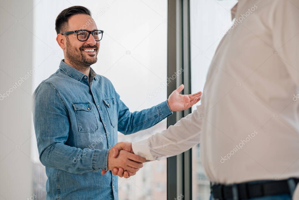 Businessman greeting job applicant businessmen handshaking over signed contract handsome entrepreneur handshake with a colleague cheerful young manager handshake with new employee getting a deal done.