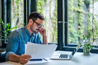 Male entrepreneur or businessman expert reading documents at office. Manager checking report. Thinking businessman lawyer analyzing deal contract papers. Company finance manager accountant.