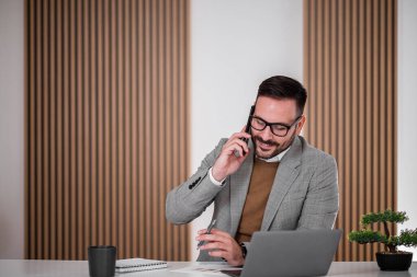 Sakin bir ofis çalışanı, şirket çalışanı ile telefonda konuşurken kalemini kurcalıyor..