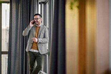 Memnuniyetle yetişkin ofis çalışanı, iş arkadaşıyla telefonda konuşuyor, gülüyor..