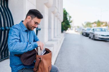 Rahat yetişkin bir adam, dışarıda çalışmaya hazırlanıyor, laptopunu iş için hazırlıyor..