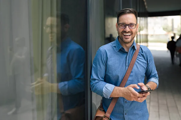 Zdjęcie Szczęśliwego Dorosłego Mężczyzny Pozującego Zdjęcia Używającego Telefonu Przed Budynkiem — Zdjęcie stockowe