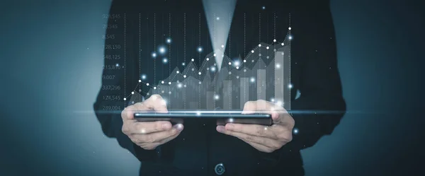 Success business concept. Businessman hand holding tablet with hologram of statistics graph and char growing graph. Planning and strategy concept.