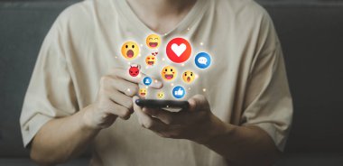 Sanal emoji sosyal medya ikonu ile akıllı telefondan sohbet ve mavi bildirim. Tatilde akıllı telefonu hologramla kullanan adam. Sosyal medya ve dijital çevrimiçi kavram.