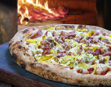 Fırında pişmiş pizza, domuz pastırması ve pırasa.