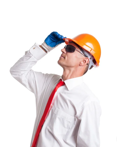 Empresário em óculos e capacete de construção olhando para cima — Fotografia de Stock