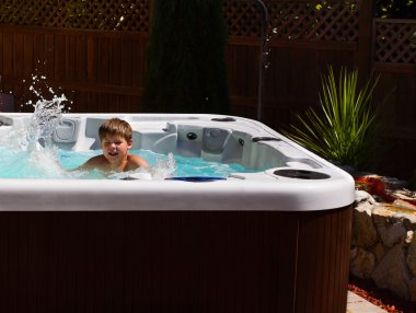 Happy boy playing in jacuzzi on the back yard clipart