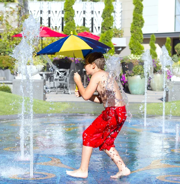 Felice ragazzo che corre attraverso l'acqua in fontana . — Foto Stock