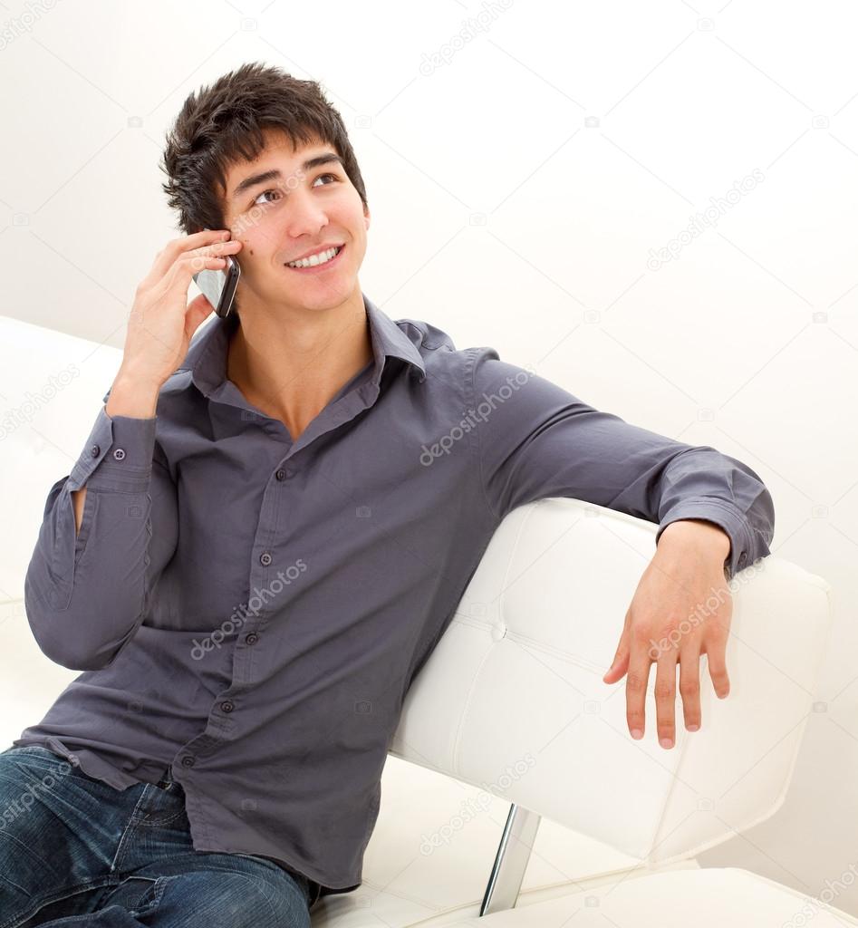 Happy smiling young man sitting on the leather sofa and talking