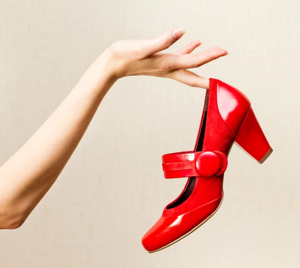 Mão feminina segurando sapatos de verniz vermelho em um salto alto . — Fotografia de Stock