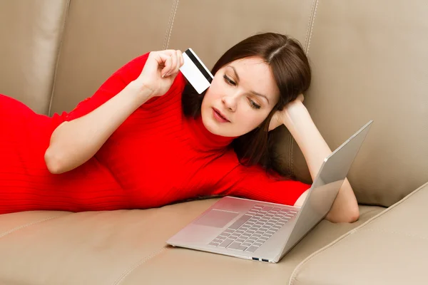 美丽的女人躺在沙发上，笔记本电脑. 免版税图库图片