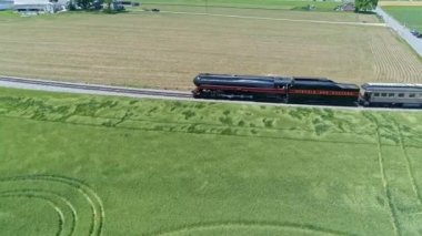 Ronks, Pennsylvania, Haziran 2021 - Güzel Bulutsuz Bir Bahar Günü 'nde Yolcu Koçlarıyla Tek Pist Verimli Çiftlik Arazide Seyahat Eden Buharlı Bir Buhar Motorunun Hava Görünümü