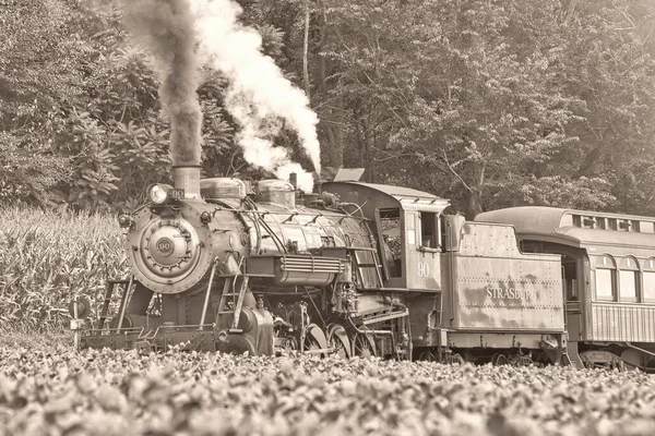 Una vista in bianco e nero di un antico treno passeggeri restaurato a vapore che soffia fumo e vapore — Foto Stock