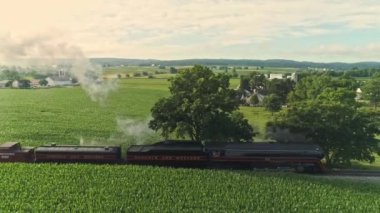 Ronks, Pennsylvania, Temmuz 2021 - Çiftlik arazilerinin havadan manzarası ve Antik Buhar Motoru Mısır Tarlalarını Erken Bir Yaz Sabahında Geçiyor